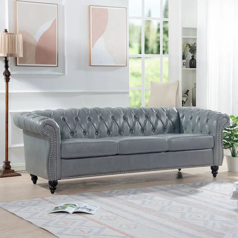 84.65 Divano Chesterfield in finta pelle trapuntata con braccioli arrotolati